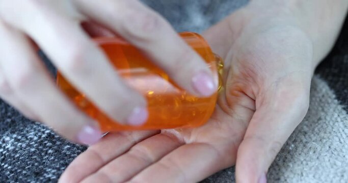 Gold capsules are poured from jar onto hand