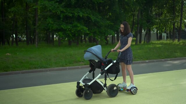 Young woman walks with a stroller on a hoverboard