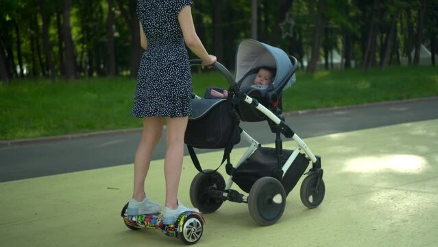 A young mother carries a stroller while standing 
