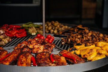Grilled vegetables and meat. Food market: Large metal grill for frying.  Tomatoes, potatoes, pepper, zucchini, steak, chicken, mushrooms