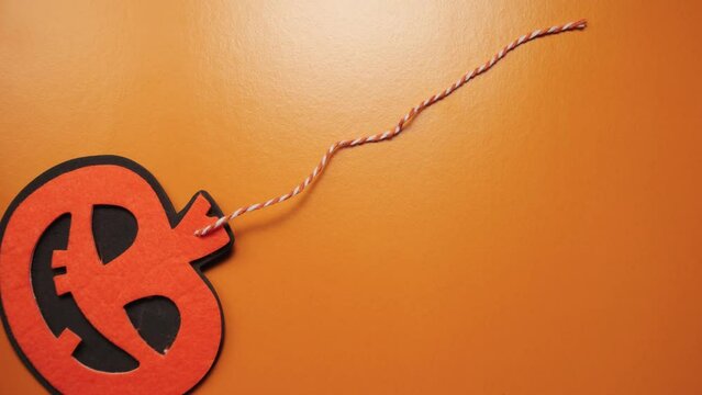 Halloween pumpkin pendant moving from left to right on an orange background. Jack's Lantern is the symbol of October 31. Stop motion animation