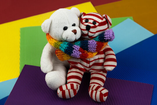 Two different teddy bear toys are wrapped in a rainbow-colored scarf. Concept National LGBT History Month - Powered by Adobe