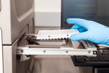 Scientist loading samples to a RT-PCR thermal cycler at the laboratory. Real-time polymerase chain...