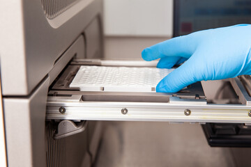 Scientist loading samples to a RT-PCR thermal cycler at the laboratory. Real-time polymerase chain...