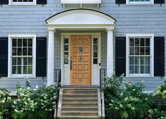 Front door of traditional two story suburban clapboard house with shutters