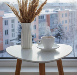 cup of coffee on white table by window on winter