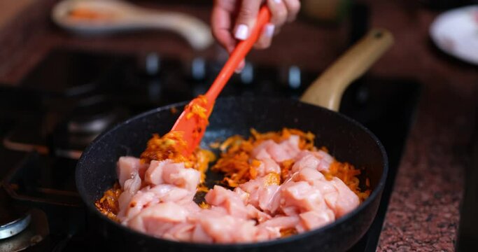 Shredded carrots and chicken fillet meat in frying pan