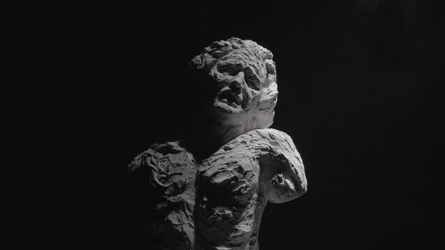 A white statue of a man. A close-up shot on a black background.