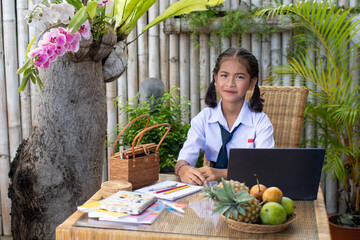 Obraz premium Asia young girl in school uniform sitting at the table and studying with a laptop.