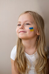 little Ukrainian woman with a picture of the flag of Ukraine and the heart of peace