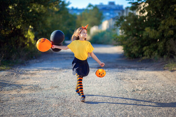 A girl in a Halloween costume is on the way with balloons. Orange Halloween Outfits