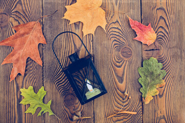 Autumn composition with a candlestick lantern in the center, autumn dry leaves on a wooden...