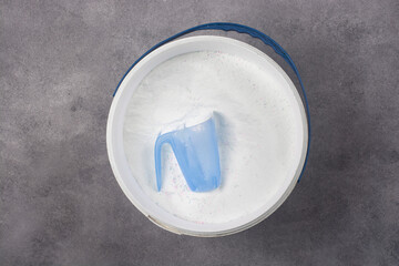 A measuring cup in a bucket of washing powder.