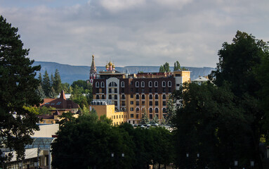Fototapeta na wymiar Cityscape - panoramic top view of Kislovodsk in Russia with historical buildings and green foliage of trees against the background of a mountain and a cloudy sky