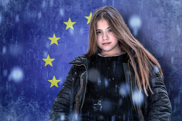 Teenage girl on a frozen background with the flag of the European Union. The concept of the crisis in Europe in winter. Energy crisis.