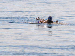 Fototapeta premium A girl on an inflatable circle is resting on the river. Swimming on an inflatable circle in summer on the river. The beach by the river. Spray and sun by the river.