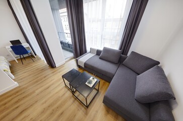 Jasny salon w apartamencie z szarą kanapą, stolikiem kawoym i telewiziorem