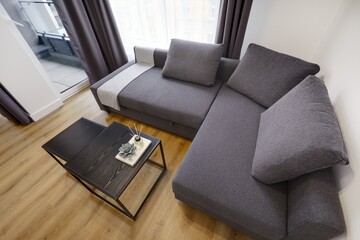 Jasny salon w apartamencie z szarą kanapą, stolikiem kawoym i telewiziorem