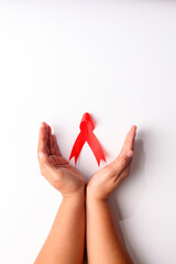 Close up photo of woman's hand holding red ribbon over white background with copyspace. Aids day concept