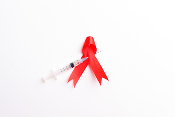Medical syringe and red ribbon over white background. Aids day concept