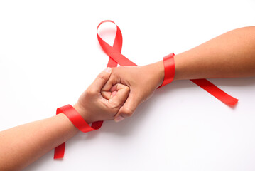 Two hands holds each other with red ribbon. Aids day concept - Powered by Adobe