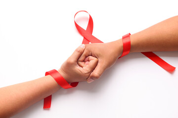 Two hands holds each other with red ribbon. Aids day concept
