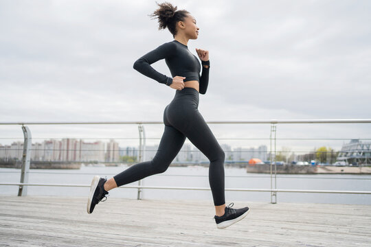 A female runner is running fitness training in a tight-fitting tracksuit.