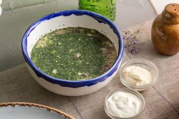 Cold summer soup with cucumber and fresh herbs Okroshka in white bowl on the table