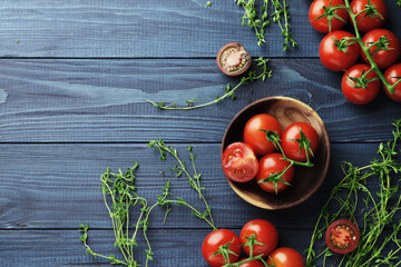 Composition of fresh ripe cherry tomatoes, thyme and spices on blue wooden background