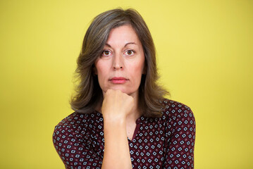 Studio portrait of an attractive 50 year old woman on yellow background
