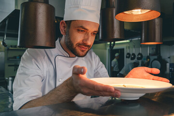 Professional chef checks dish just before serving it to customer in restaurant