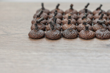 Hats with tails from acorns, laid symmetrically on a wooden background closeup.