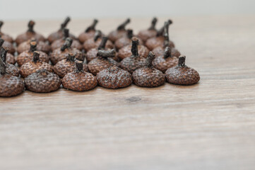 Hats with tails from acorns, laid symmetrically diagonally on a wooden background closeup.