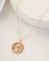 Fashion bijouterie - a gold chain with a pendant on a white stand