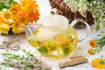 Glass tea kettle of healthy herbal tea, hyssop, calendula, balm mint medicinal herbs on white...