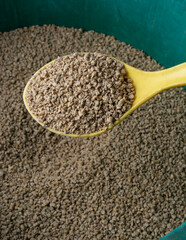 spoon full of chicken feed crumble, semi-loose variety made from pellets cracked into smaller...