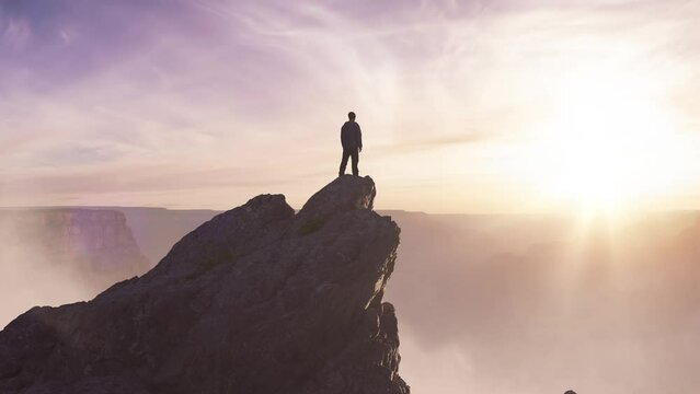 Epic Adventure Composite of Man Hiker on top of a rocky mountain. Dramatic Sunset Sky. 3d Rendering peak. Background landscape from North America. Freedom Concept. Animation