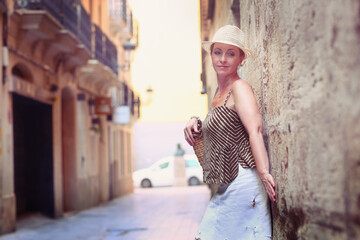 blond beautiful woman in straw hat closeup portrait in Spanish old street line