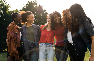 Multiracial friends embracing together on park outdoor - Portrait of ladies students outside in the university campus