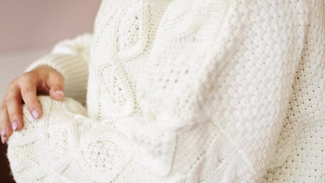 Hand touching knitted wool cloth warm fluffy white sweater. Handcraft knitting woolen fabric surface. 