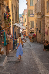 Woman in front of a old french leather shop, looking at window on a summer day