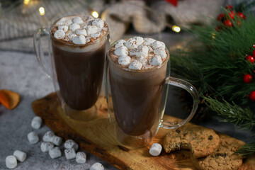 hot chocolate in a glass mugs with mini marshmallows on grey table, blurred xmas background 
