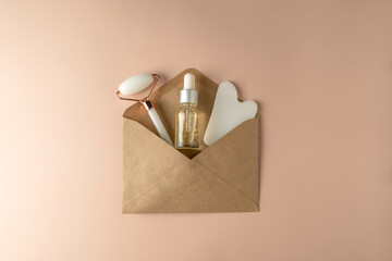 A natural transparent hyaluronic face serum, face roller and guasha massager lying in a brown envelope