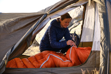 Female tourist fastening sleeping bag in tent