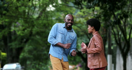 Happy carefree black couple dancing together outside in street