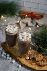 hot chocolate in a glass mugs with mini marshmallows on grey table, blurred xmas background 