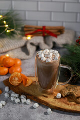 hot chocolate in a glass mug with mini marshmallows on wooden plate, blurred xmas background 