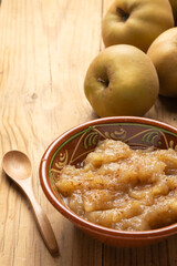 Top view of a rustic bowl with applesauce on a table with pippin apples and a spoon, vertically, with copy space