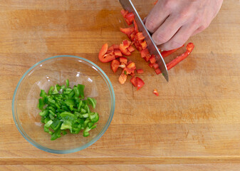 Cook's hand cutting vegetables on a chopping board. Copy space.