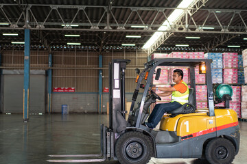 Asian male driver driving forklift to shipping delivery product in the warehouse distribution. import export logistic career, worker working at industrial factory. © winnievinzence